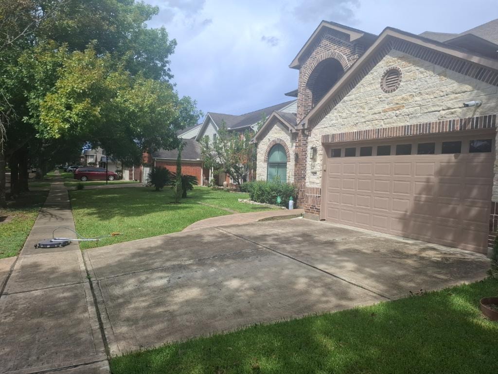Brick house driveway before pressure washing — stained concrete